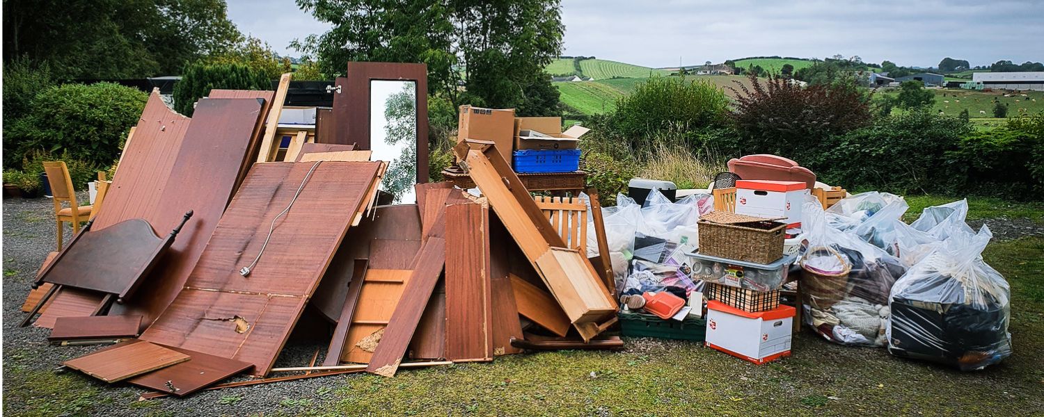 Large pile of bulky waste including wooden panels and mirrors outdoors
