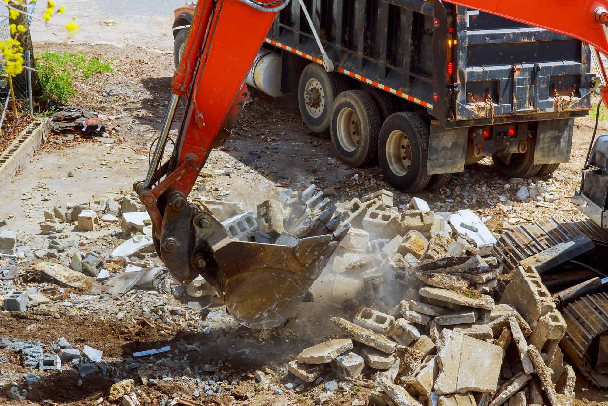 Excavator loads construction waste into of material for disposal from construction a home renovation